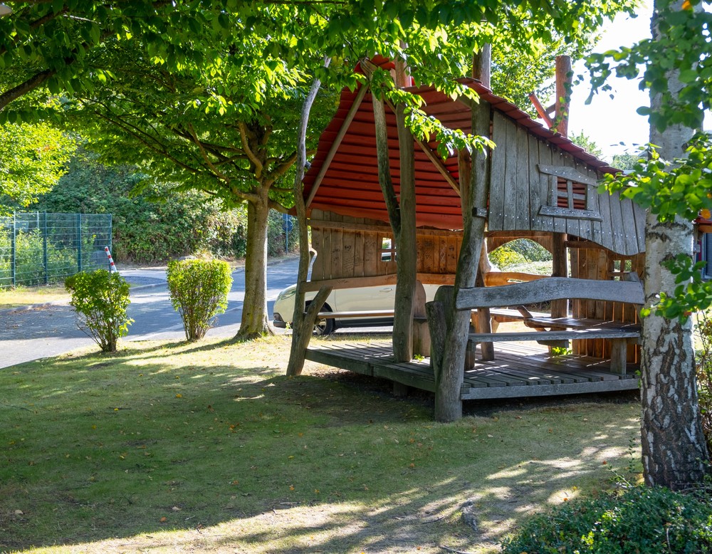 Das Bild zeigt ein großes Baumhaus, umgeben von grünen Bäumen.