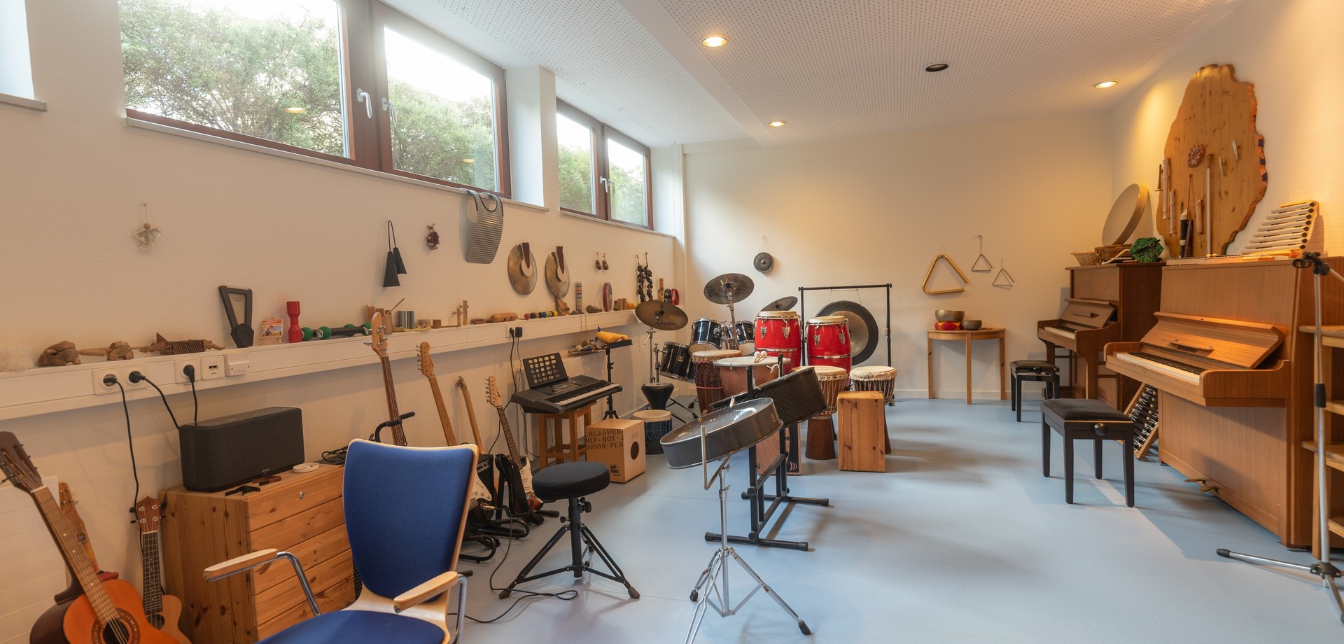 Das Bild zeigt einen Musikraum mit vielen unterschiedlichen Musikinstrumenten.