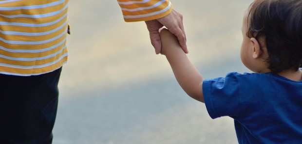 Das Bild zeigt eine Mutter, die ihr kleines Kind an der Hand hält. Das Bild zeigt eine Mutter, die ihr kleines Kind an der Hand hält.