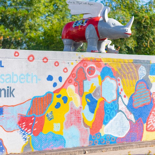 Das Bild zeigt eine bunte Nilpferd-Statue, die auf einer bunt angemalten Garage steht.