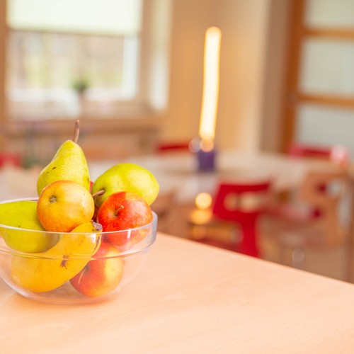 Das Bild zeigt eine Obstschale mit Äpfeln, Birnen und Bananen, die auf eine Holztisch steht.