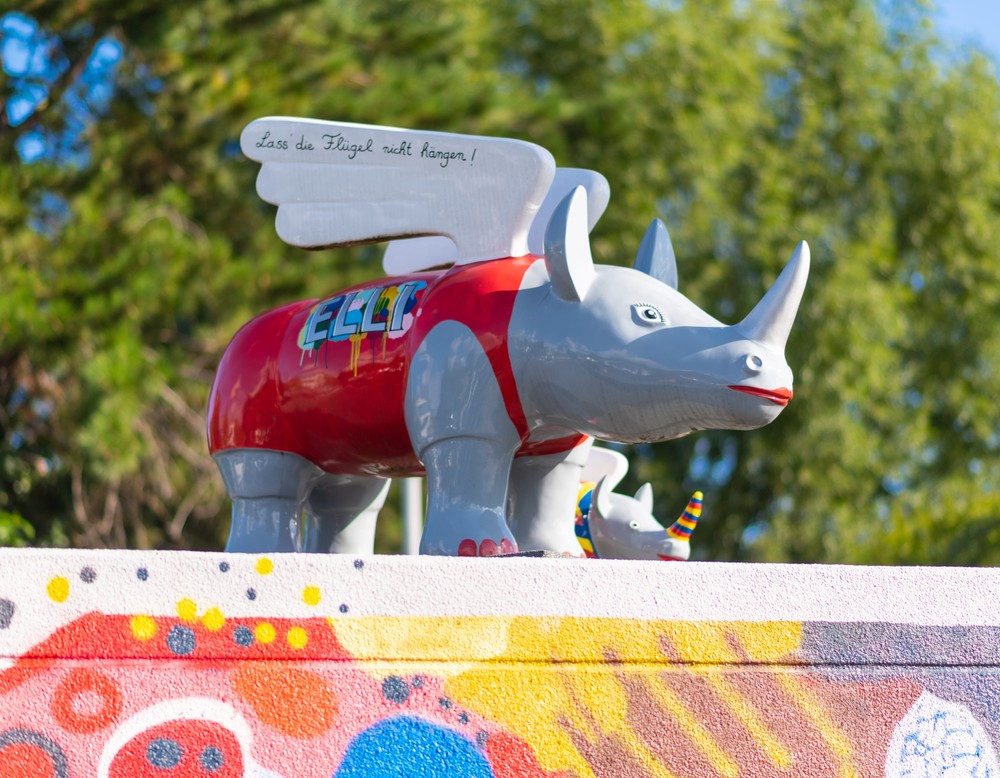 Das Bild zeigt zwei kleine, kunterbunte Nashorn-Figuren, die auf einem Dach stehen.