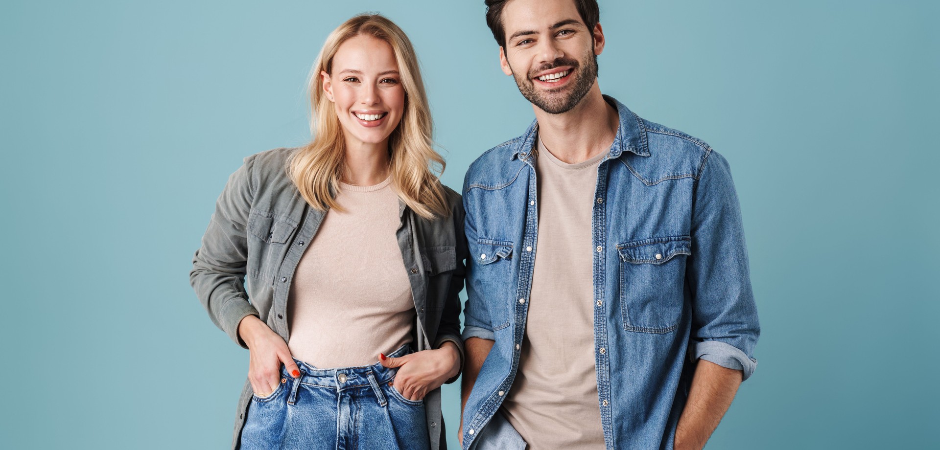 Das Bild zeigt einen jungen Mann und eine junge Frau, die nebeneinander stehen und in die Kamera lächeln